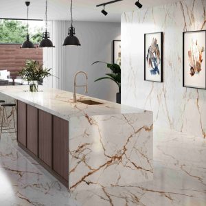 Modern kitchen interior featuring a luxurious island and wall with white marble accented by gold veining, complemented by contemporary pendant lights and large framed artwork, creating a sophisticated and stylish atmosphere.